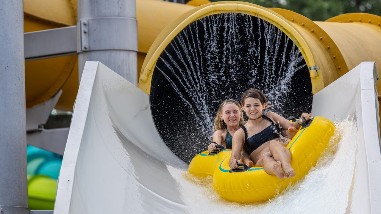 Two guests enjoying the Liquid Lightning water slide in Water World.